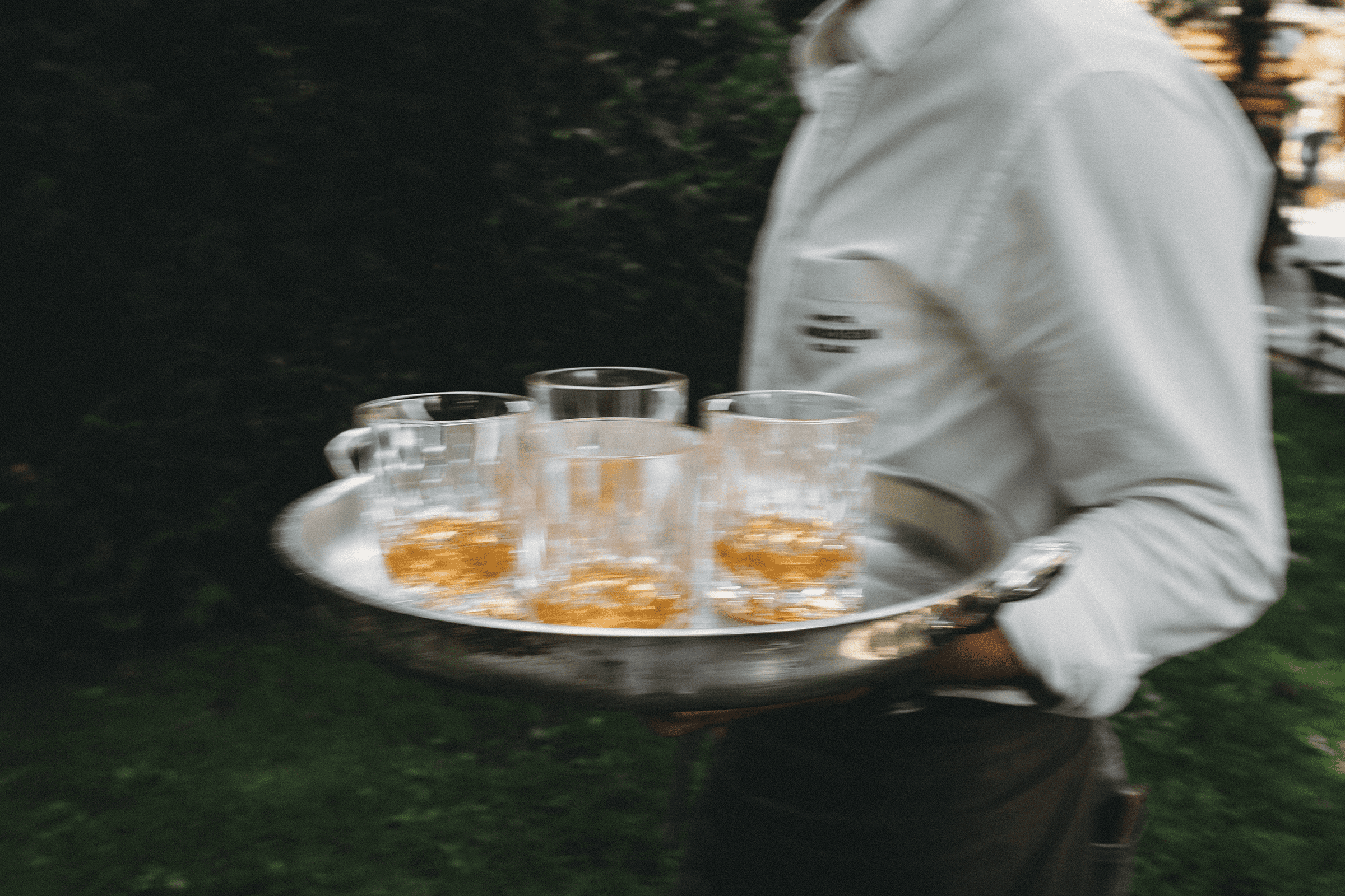 Ein Kellner serviert mehrere Gläser Amaro Amarill pur auf Eis.