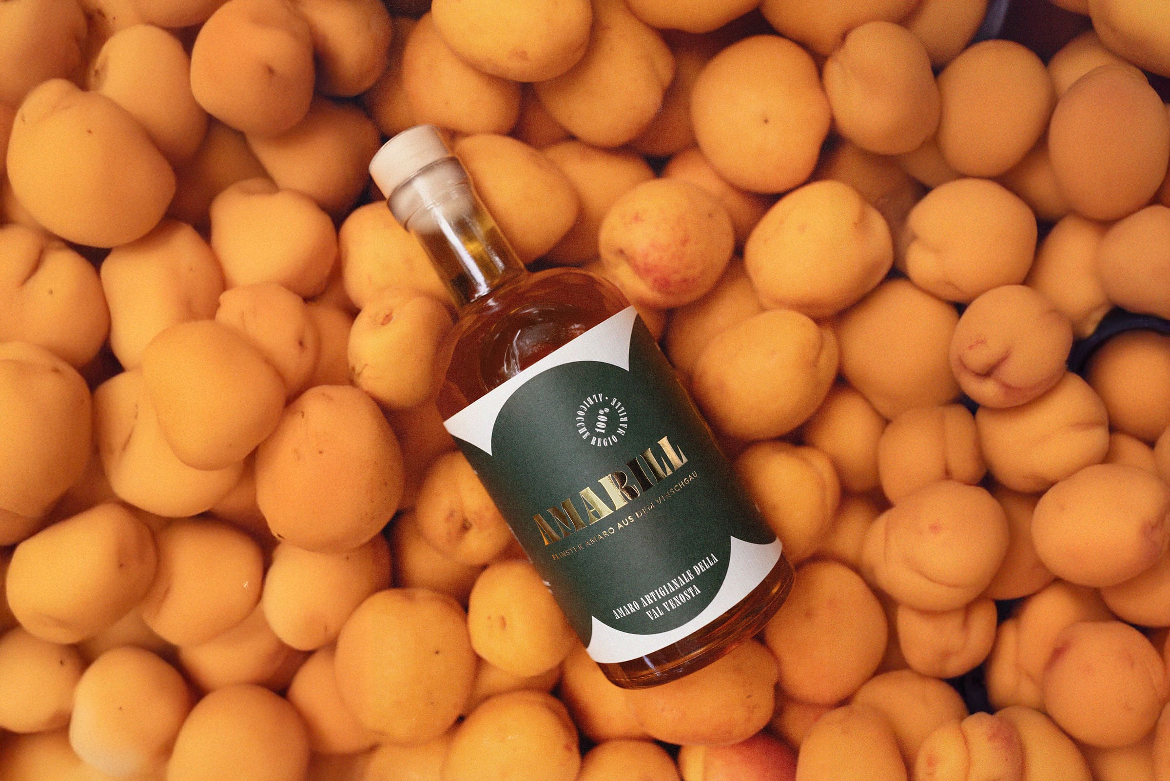 Eine Flasche Amaro Amarill, im Hintergrund unzählige Vinschger Bergmarillen.